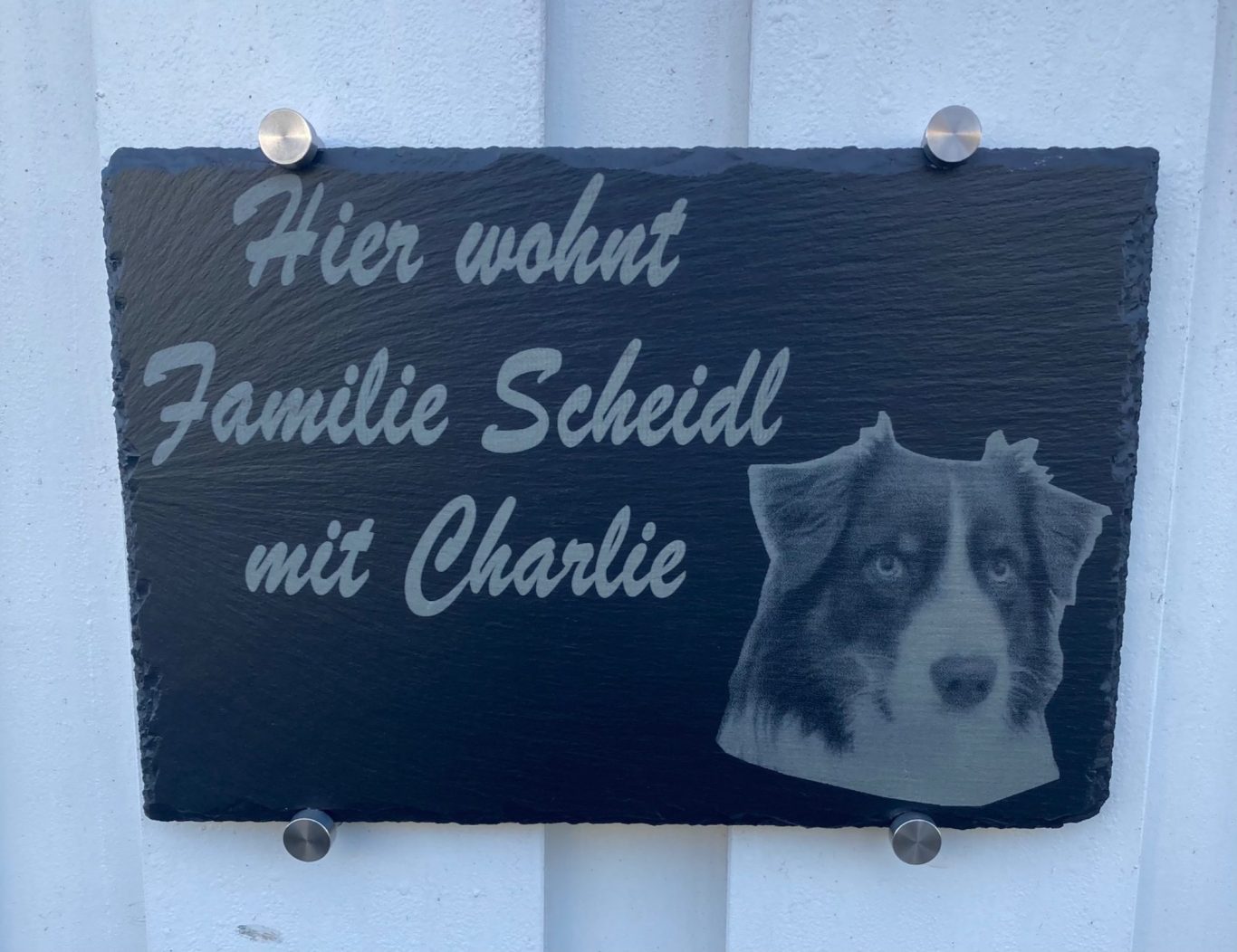 Schild mit der Aufschrift „Hier wohnt Familie Scheidl mit Charlie“ und Hundebild.